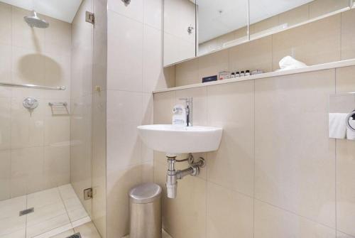 a white bathroom with a sink and a shower at Luxury two-beds harbour views apartment in Darwin