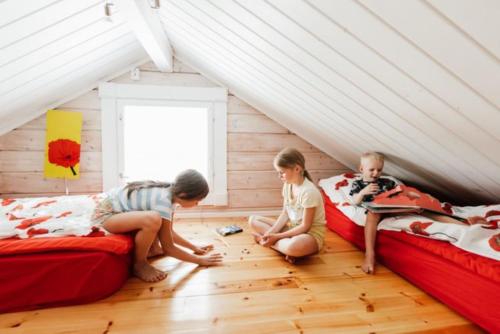 three children sitting on beds in a attic at Pikku Torppa Cottage in Kotka