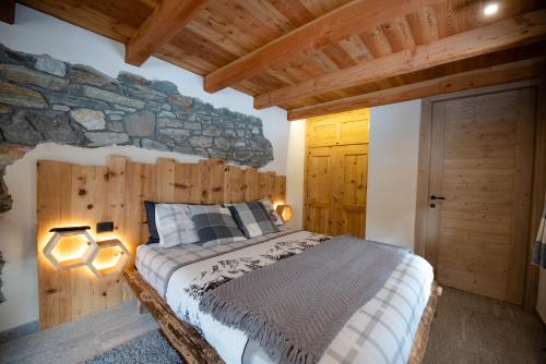 a bedroom with a bed and a stone wall at Le Camere di Naturalys - ospitalità in azienda agricola in Gaby