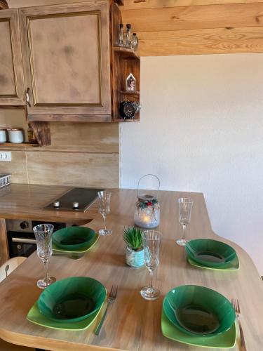 a wooden table with green plates and glasses on it at Family home MASA in Žabljak