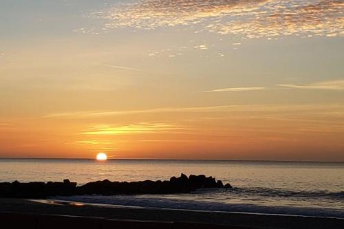 a sunset over the ocean with rocks in the water at Studio refait à neuf Ave St Maurice in Palavas-les-Flots