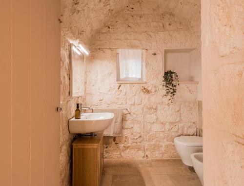 bagno in pietra con lavandino e servizi igienici di VILLA OSTUNI ONE mit Pool, Gästehaus & Glamping a Ostuni