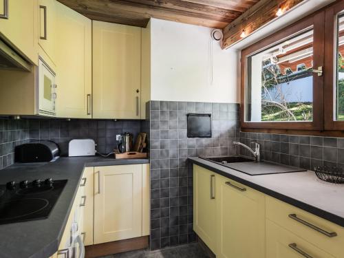 d'une cuisine avec des placards jaunes, un évier et une fenêtre. dans l'établissement Location Appartement Duplex 2 Chambres - Proche Pistes et Golf à Megève - Terrasse et Parking - FR-1-453-26, à Megève