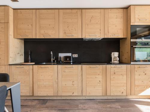 - une cuisine avec des placards en bois et un mur noir dans l'établissement Appartement rénové 4 pers. au centre de Megève - Balcon, parking, TV, Wifi - FR-1-453-66, à Megève