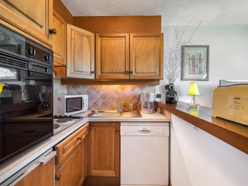 - une cuisine avec des placards en bois et un lave-vaisselle blanc dans l'établissement Studio 4 pers - Balcon - Proximité pistes et golf - TV - Garage - Animaux OK - Tennis en été - FR-1-453-82, à Megève
