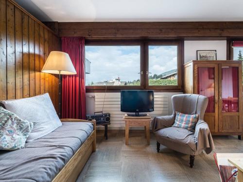 - un salon avec un lit, une télévision et une chaise dans l'établissement Studio cosy à Megève, proche pistes Rochebrune et centre, avec parking et TV - FR-1-453-124, à Megève