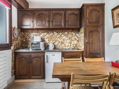 une cuisine avec des placards en bois et une table avec des chaises dans l'établissement Studio Megève, 1 pièce, 2 personnes - FR-1-453-124, à Megève
