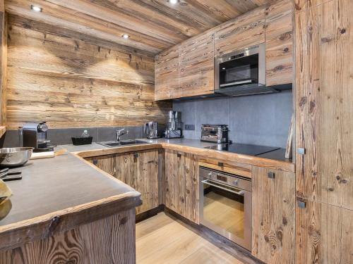 une cuisine avec des armoires en bois et un four à plaques de cuisson dans l'établissement Appartement Duplex 4 Chambres Rénové avec Cheminée, Piscine, Tennis, Proche Télécabine - Megève - FR-1-453-25, à Megève