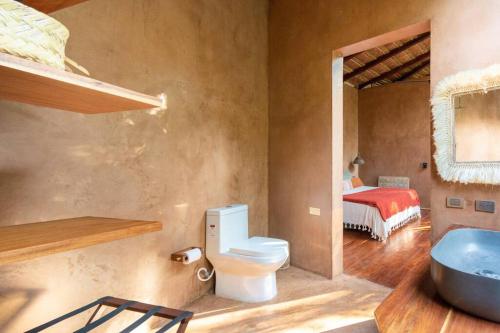 a bathroom with a toilet and a sink and a bed at OJO DE AGUA. Design+pool. Vive la auténtica selva! in Tulum