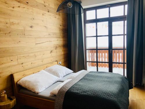 a bedroom with a bed and a large window at Strunzova Pila - apartmány s wellness 2,06 a 3,03 in Kvilda