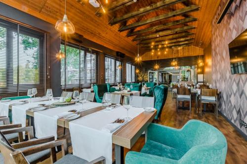 a restaurant with white tables and blue chairs at Hotel Mazurski Raj in Ruciane-Nida