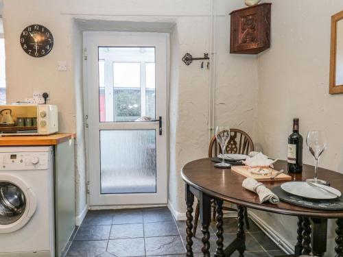 a kitchen with a table and a washing machine at Lavender Cottage in Grange Over Sands