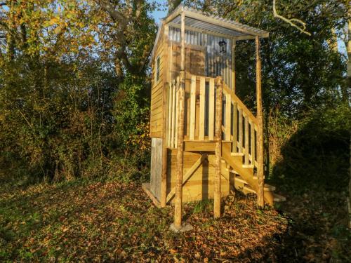 a wooden out house sitting in the woods at The Wagon at Burrow Hill in Ottery Saint Mary