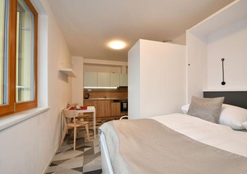 a bedroom with a white bed and a kitchen at EFI Residence Holzova 28 in Brno