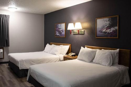 a hotel room with two beds with white sheets at New Victorian Inn & Suites-Norfolk in Norfolk