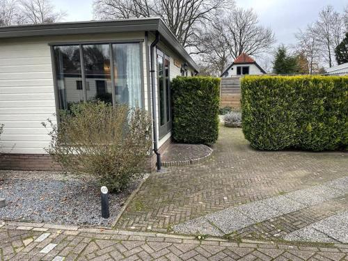 una casa con ventana y algunos arbustos en Gezellig chalet op de prachtige Veluwe en Putten