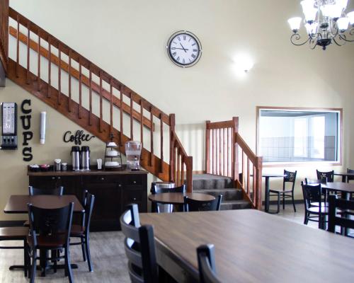 a dining room with a table and chairs and a clock at New Victorian Inn & Suites-Norfolk in Norfolk
