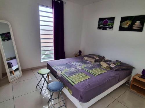 a bedroom with a bed and two stools in it at Appartement charmant aux Trois-Îlets 40 m² avec balcon privé in Les Trois-Îlets