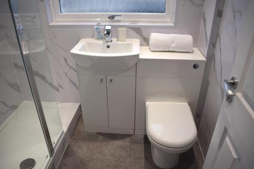 a bathroom with a sink and a toilet and a window at Kelpies Serviced Apartments- Cromwell Apt in Falkirk