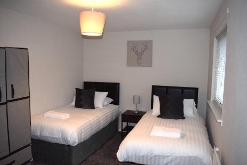 a bedroom with two beds and a lamp at Kelpies Serviced Apartments- Cromwell Apt in Falkirk