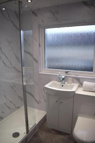 a bathroom with a shower and a sink and a toilet at Kelpies Serviced Apartments- Cromwell Apt in Falkirk