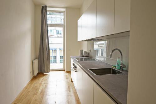 a kitchen with white cabinets and a sink and a window at Vienna City Apartments Ottakring in Vienna