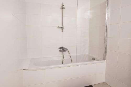 a bath tub with a faucet in a white bathroom at Vienna City Apartments Ottakring in Vienna