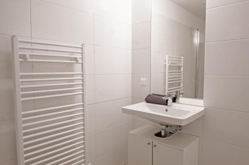 Baño blanco con lavabo y espejo en Vienna Living Apartments - Ottakring en Viena