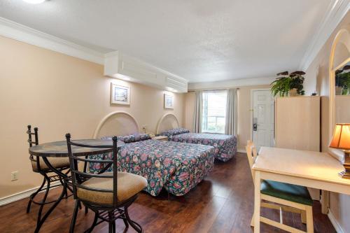 Habitación con 2 camas, mesa y sillas en Edgewater Inn - Biloxi Beach en Biloxi
