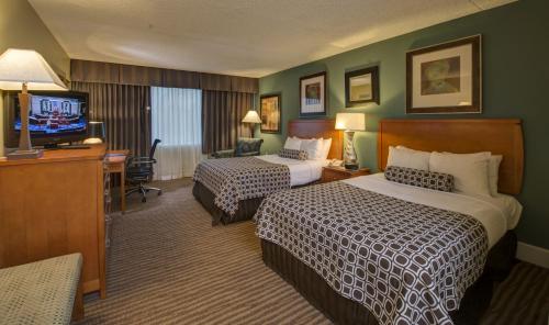 a hotel room with two beds and a flat screen tv at The Rockville Hotel, a Ramada by Wyndham in Rockville