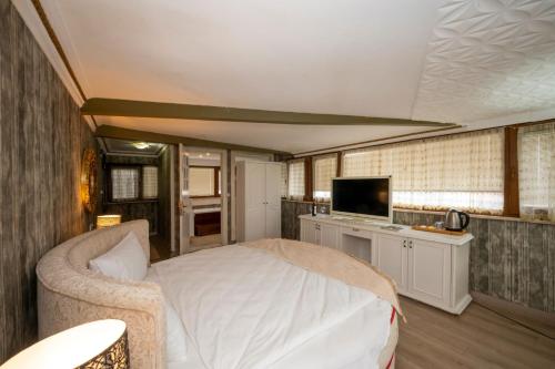 Fuat Bey Palace Hotel & Suites في إسطنبول: غرفة نوم فيها سرير وتلفزيون