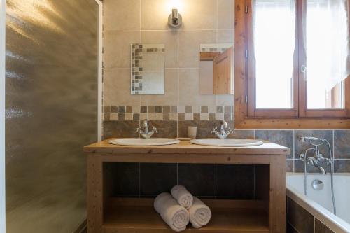 ein Badezimmer mit zwei Waschbecken, einem Fenster und einer Badewanne in der Unterkunft Chalet Matsuzaka - chambres d'hôtes de luxe in La Rosière
