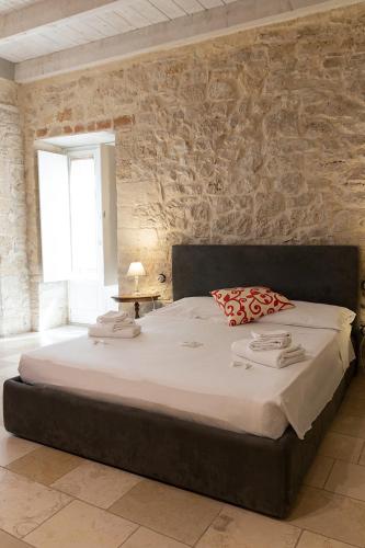 a large bed in a room with a stone wall at Graffiti Living - Santa Rita - Rooms in Corato