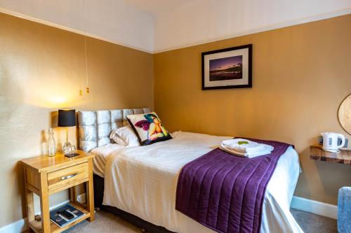 a small bedroom with a bed and a night stand at Holly Lodge Guest House with FREE off site health club in Windermere