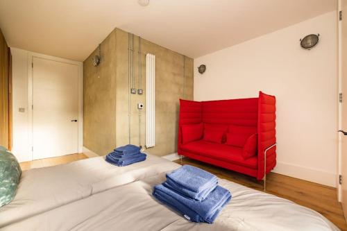 a room with two beds and a red couch at Cool Loft in fashionable East London in London