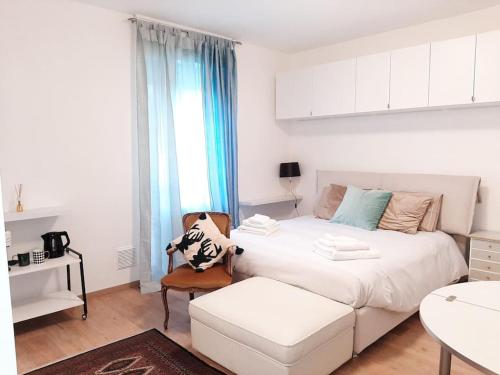 1 dormitorio blanco con 1 cama blanca y 1 silla en CASA VACANZE FILO, en Pordenone
