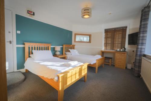 a bedroom with two beds and a desk in it at The Star Inn in Lingfield