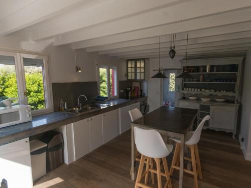 - une cuisine avec une table et des chaises blanches dans l'établissement Maison rénovée avec jardin près de la plage et des commerces, déco soignée, animaux acceptés - FR-1-418-29, à Sauzon