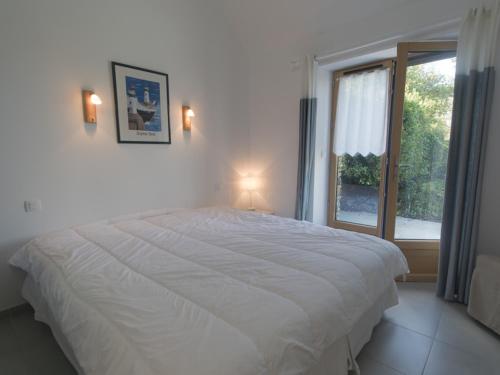 een wit bed in een slaapkamer met een raam bij Maison Le Palais, 2 pièces, 3 personnes - FR-1-418-88 in Le Palais