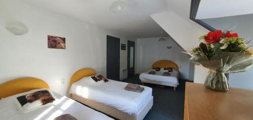 ein Hotelzimmer mit 2 Betten und einer Vase aus Blumen in der Unterkunft Grand Hotel de la Vallée in Cheylade