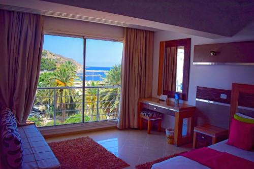 Schlafzimmer mit einem Bett, einem Schreibtisch und einem großen Fenster in der Unterkunft Marina Prestige Tabarka in Tabarca
