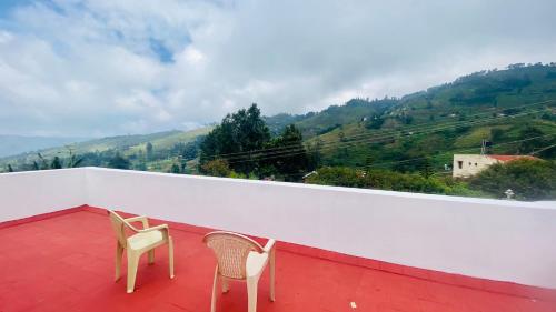 two chairs on a balcony with a view of a mountain at Mountain Abode in Kodaikānāl