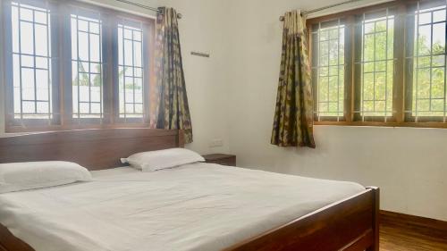 a bedroom with a large bed and windows at Mountain Abode in Kodaikānāl