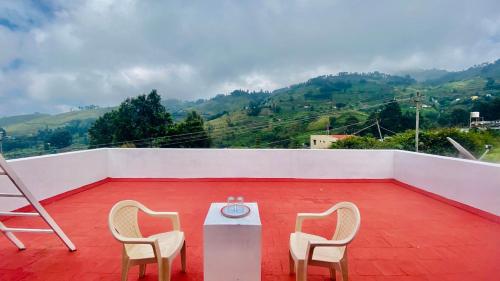 a room with two chairs and a table on a roof at Mountain Abode in Kodaikānāl