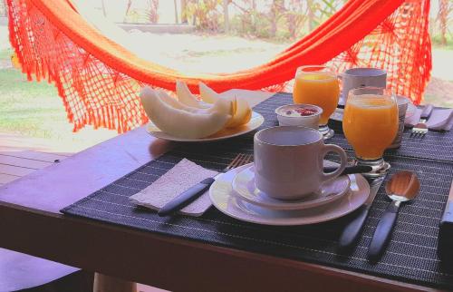 a table with a breakfast of coffee and orange juice at D'Ajuda Flat Taipu Bangalôs in Taipu