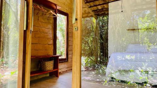 a glass door of a room with a bed outside at Chalés Vila Floresta in Alto Paraíso de Goiás