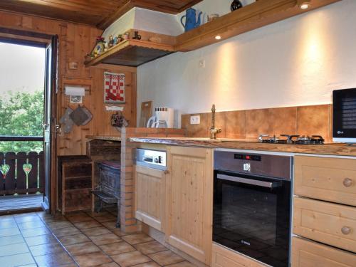 une cuisine avec des armoires en bois et un four à plaques de cuisson dans l'établissement Chalet Savoyard en Bordure des Pistes avec Liaison Facile vers le Centre de Morzine - FR-1-524-11, à Morzine