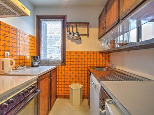 Il comprend une cuisine dotée d'un mur en carrelage orange. dans l'établissement Appartement 2 Pièces, Proche école de ski, Animaux admis, Balcon - FR-1-524-79, à Morzine