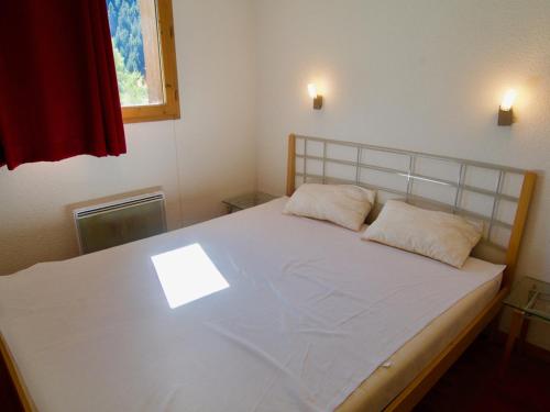 ein Schlafzimmer mit einem großen weißen Bett mit zwei Kissen in der Unterkunft Appartement Valfréjus, 2 pièces, 6 personnes - FR-1-468-26 in Valfréjus