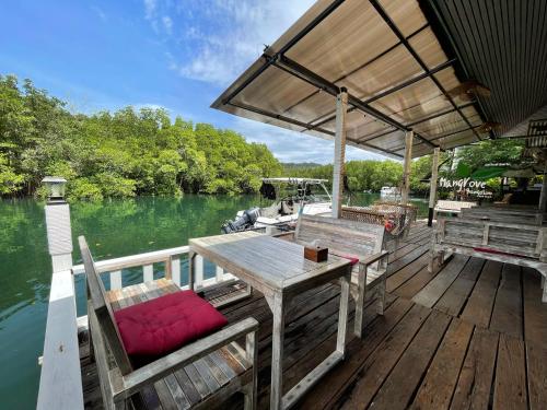 une terrasse en bois avec une table et des chaises sur un bateau dans l'établissement Mangrove bungalow & restaurant, à Ko Kood